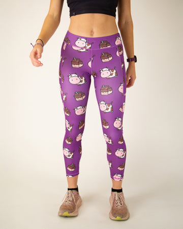 Runner is wearing ChicknLegs in the women's drawstring leggings with pockets in the choccy cow design. The print has brown and white cows with chocolate milk on a purple background.