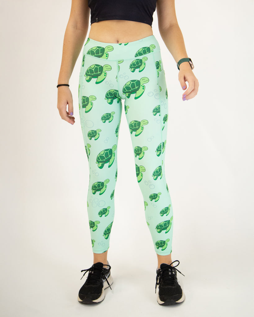 Runner is wearing ChicknLegs in the women's drawstring leggings with pockets in the sea turtles design. The print has bubbles and turtles on it that are green on a light solid green background.