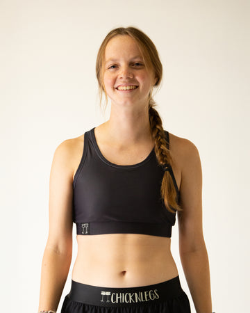 Runner is wearing ChicknLegs in the women's OG Sports Bra has a back pocket for exercise, running, workout, gym, and every day lifestyle. The print is a solid black color.