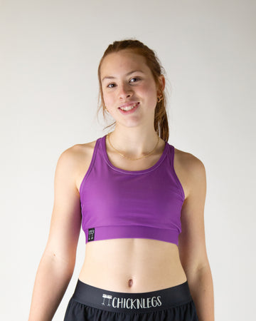 Runner is wearing ChicknLegs in the women's OG Sports Bra has a back pocket for exercise, running, workout, gym, and every day lifestyle. The print is the deep purple solid color. Great for matching with the choccy cow shorts.