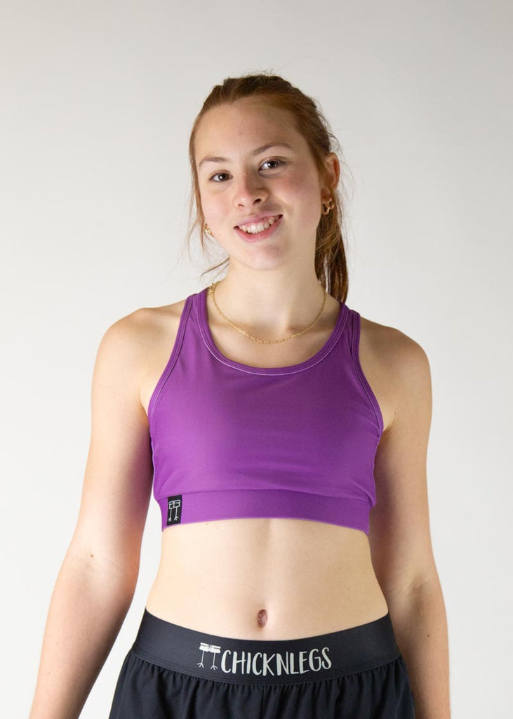 The model is a runner who is wearing Chicknlegs in thhe women's OG sports bra in the deep purple design, facing front. A close up image is shown of the model.