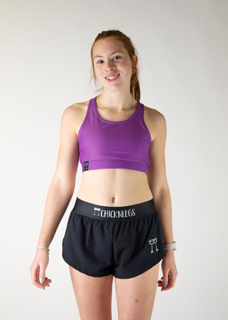 The model is a runner who is wearing Chicknlegs in thhe women's OG sports bra in the deep purple design, facing front.