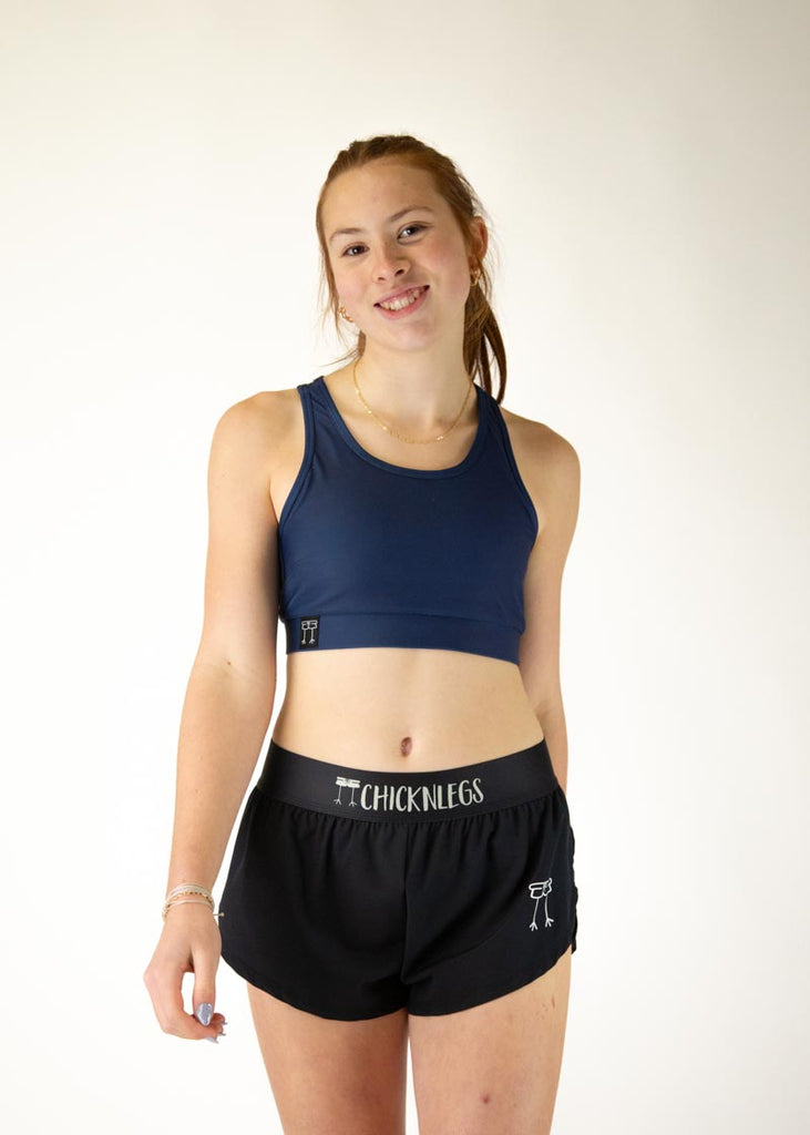 The model is a runner who is wearing Chicknlegs in the women's OG sports bra in the navy design, facing front.