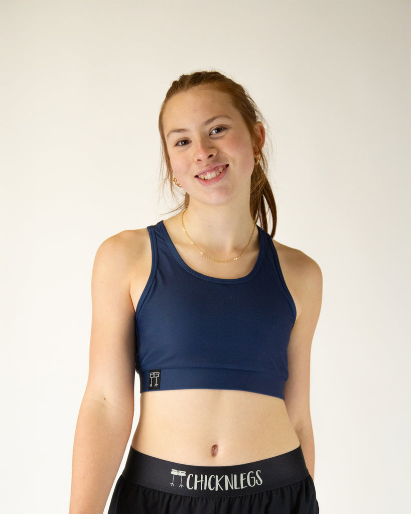 Runner is wearing ChicknLegs in the women's OG Sports Bra has a back pocket for exercise, running, workout, gym, and every day lifestyle. The print is the solid navy color.