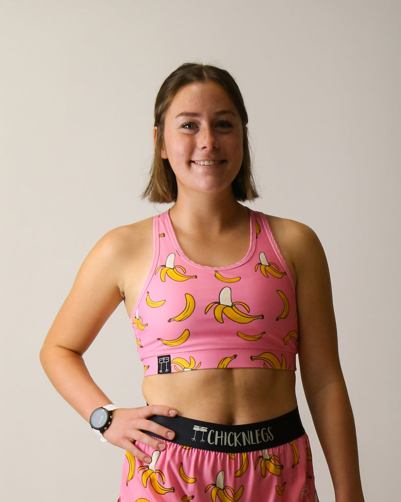 Runner is wearing ChicknLegs in the women's OG Sports Bra has a back pocket for exercise, running, workout, gym, and every day lifestyle. The print is the pink bananas which has yellow bananas on a bright pink background.