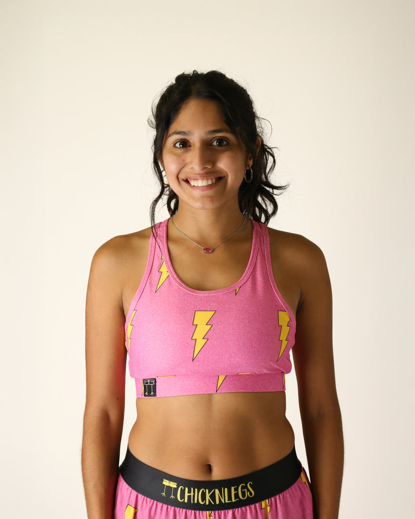 Runner is wearing ChicknLegs in the women's OG sports bra that has a pocket. Great for runners, workouts, gym, everyday lifestyle and more. The print is the hot pink bolts design which has yellow lightning bolts and a hot neon pink background.