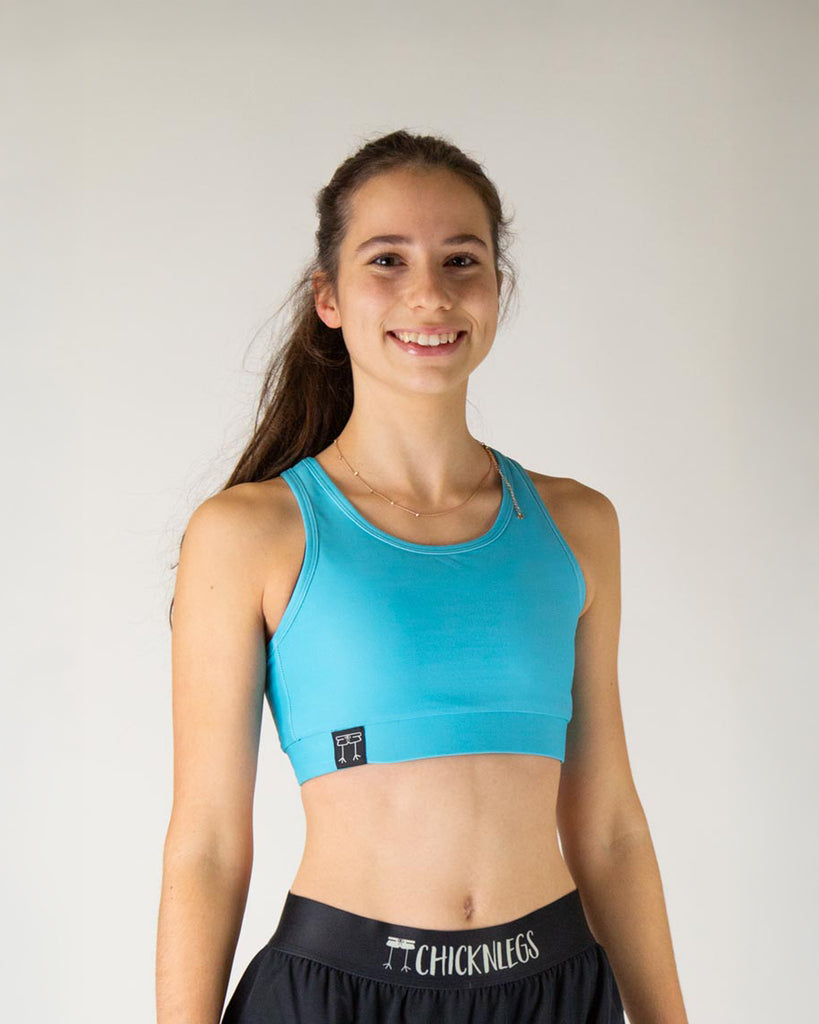 Runner is wearing ChicknLegs in the women's OG Sports Bra has a back pocket for exercise, running, workout, gym, and every day lifestyle. The print is the solid sky blue design, great for matching with the blue flamingo.