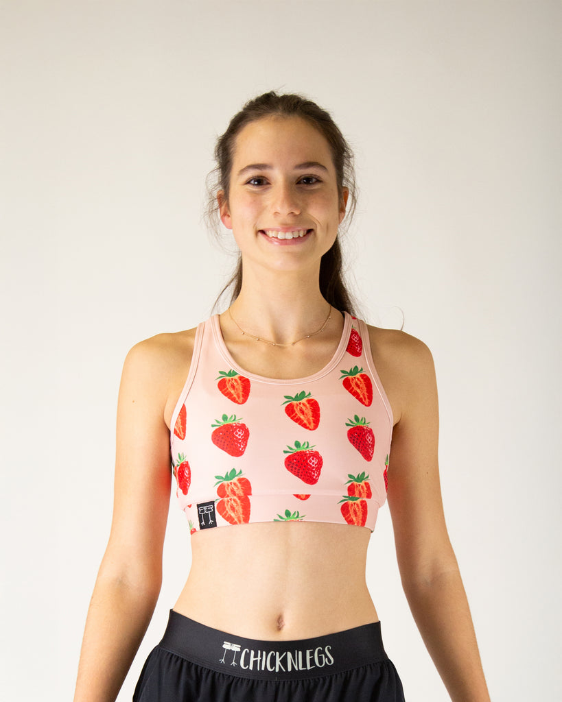 Runner is wearing ChicknLegs in the women's OG sports bra that has a pocket. Great for runners, workouts, gym, everyday lifestyle and more. The print is the strawberry szn design which has red and pink strawberries on it.