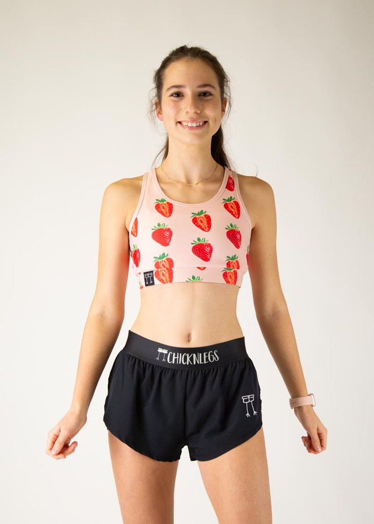 The model is a runner who is wearing Chicknlegs in the women's OG sports bra, in the strawberry SZN design, facing front.