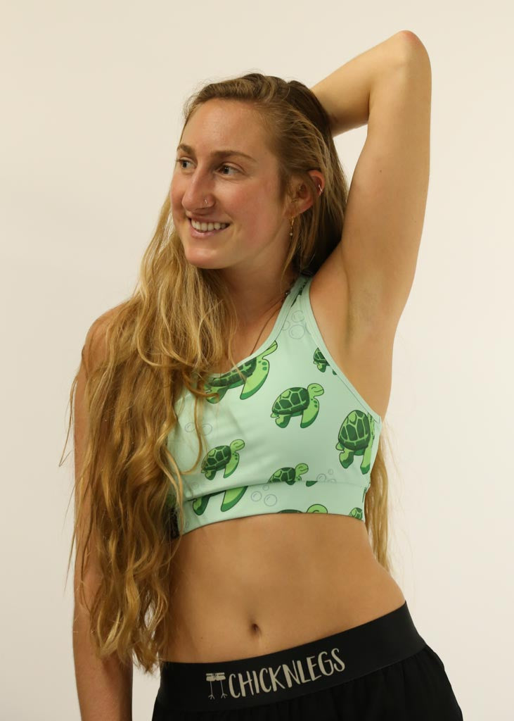 Front view of runner stretching while wearing the sea turtles OG sports bra from ChicknLegs.