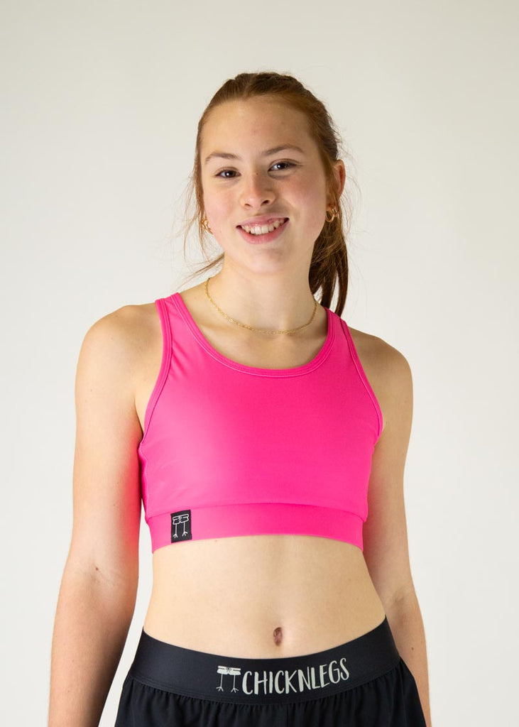 The model is a runner who is wearing Chicknlegs in the women's OG sports bra in the neon pink design, facing front. A close up image is shown of the model.