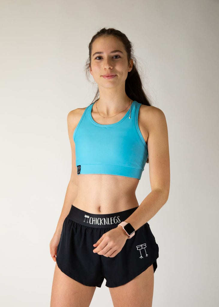 The model is a runner who is wearing Chicknlegs in the women's OG sports bra in the sky blue design, facing front.