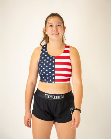 Runner is wearing ChicknLegs in the women's power crop top in the USA State Flag design. The material is lightweight and the print is the American Flag. Great for runners who love and want to rock with America.