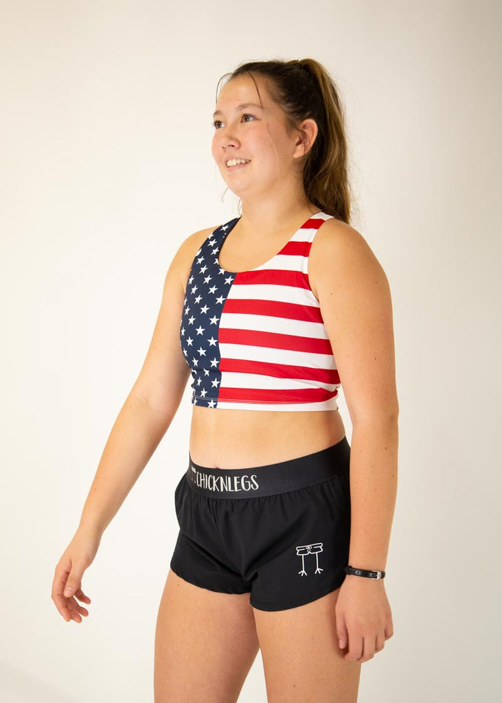 The model is a runner who is wearing Chicknlegs women's pwr USA crop top, facing left.