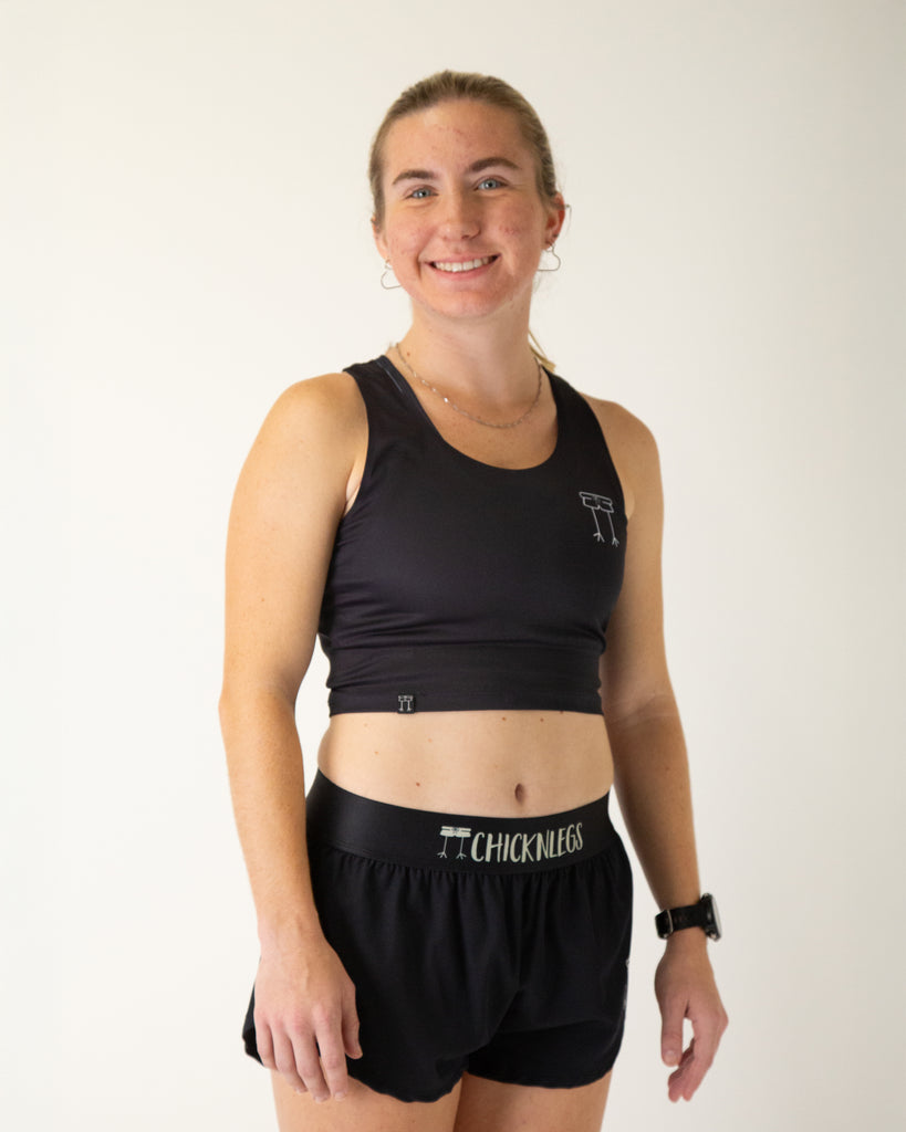 Runner is wearing ChicknLegs in the women's power crop top in the solid black design. The material is lightweight and soft.