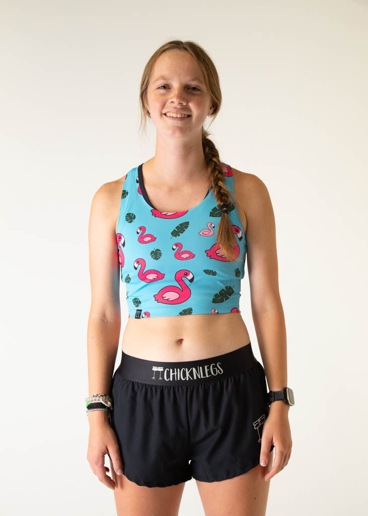 The model is a runner who is wearing Chicknlegs PWR crop top, in the blue flamingo design, facing front.