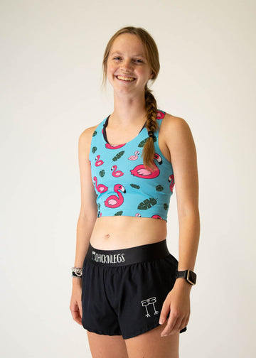 The model is a runner who is wearing Chicknlegs PWR crop top, in the blue flamingo design, facing left.