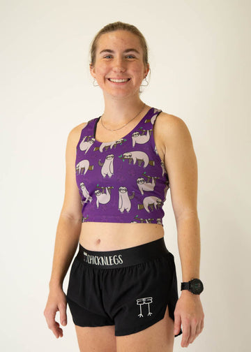 The model is a runner who is wearing Chicknlegs PWR crop top in the sloths design, facing left.