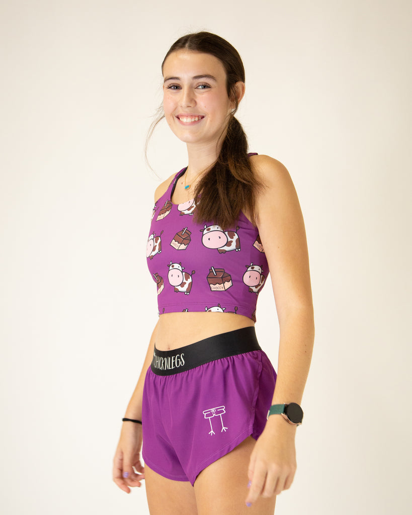 Runner is wearing ChicknLegs in the women's 1.5 in split running shorts in the deep purple design with the choccy cow PWR crop top. The outfit is a great matching fit.