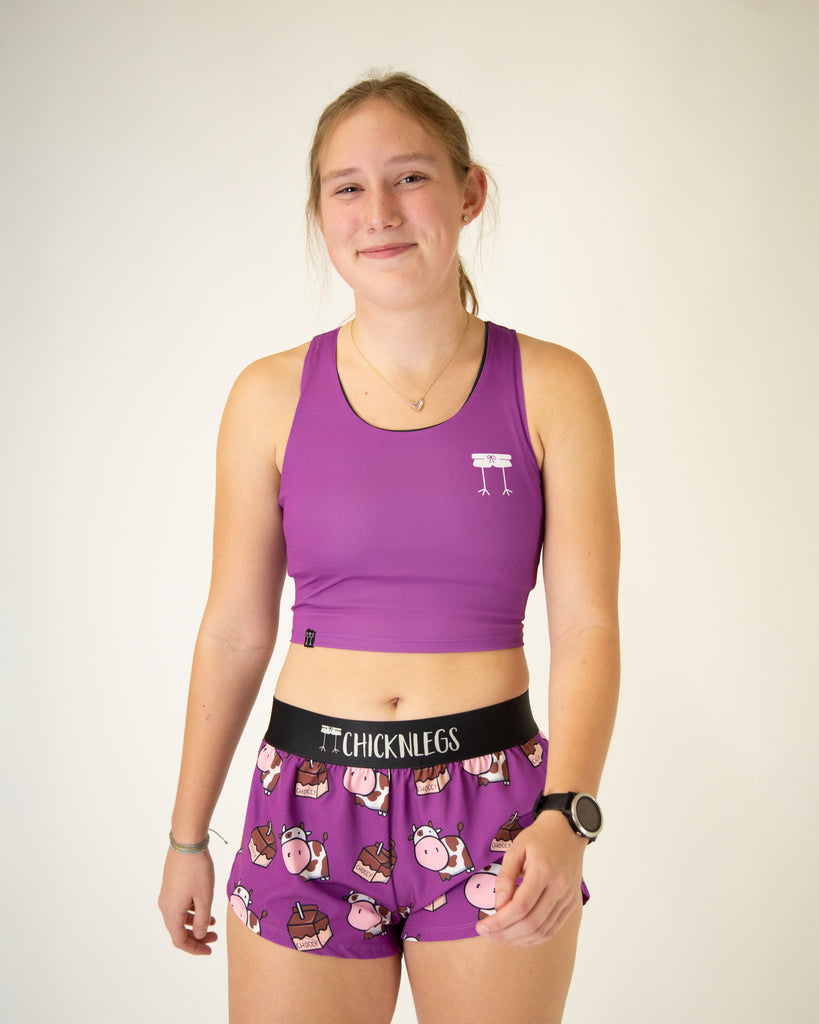 Runner is wearing ChicknLegs in the women's power crop top in the deep purple design. The material is lightweight and the print is a solid purple color.