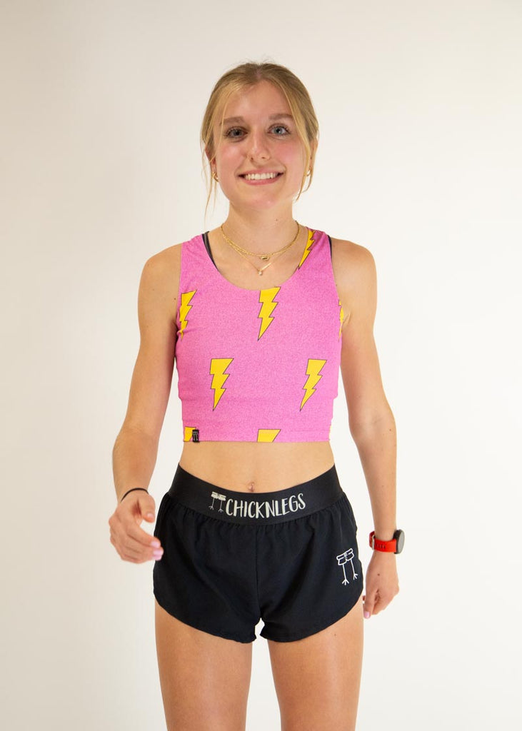 The model is a runner wearing Chicknlegs pwr crop top in the hot pink bolts design, facing front.