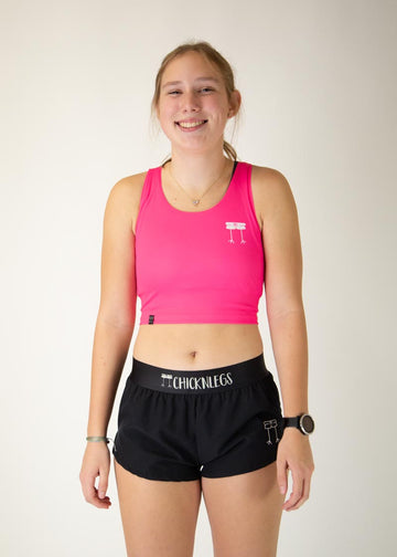 The model is a runner who is wearing Chicknlegs women's Neon Pink pwr crop top, facing front.