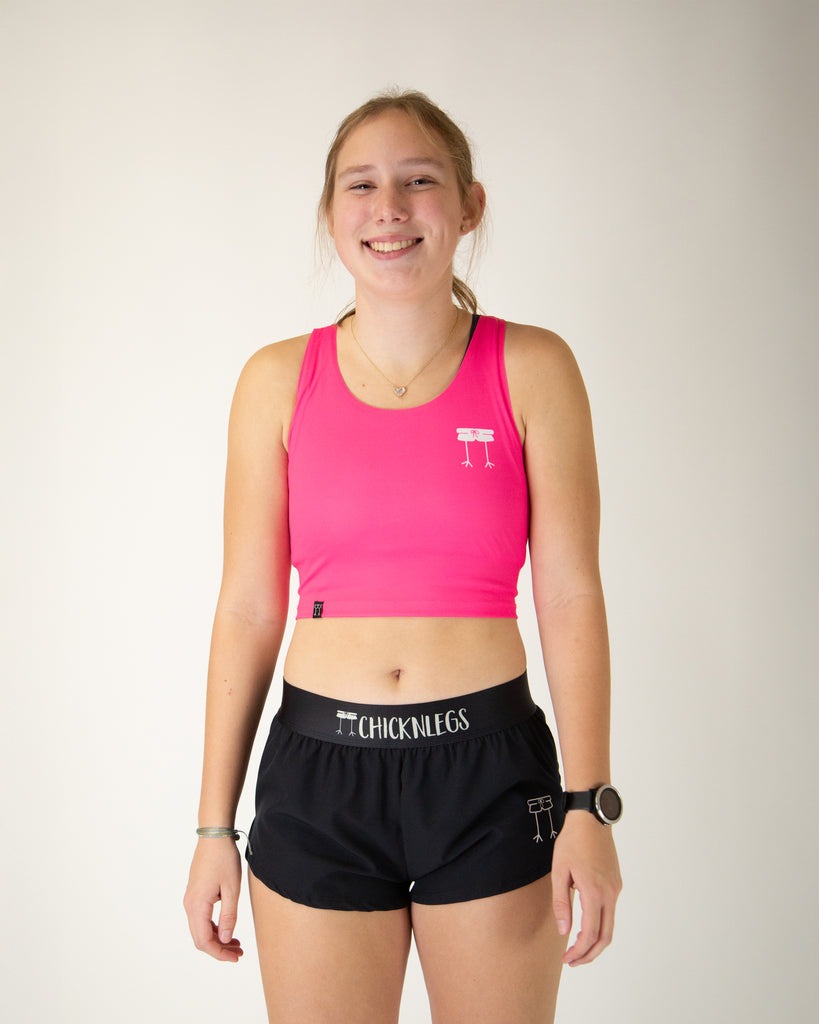 Runner is wearing ChicknLegs in the women's power crop top in the neon pink design. The material is lightweight and the print has a solid neon pink color.