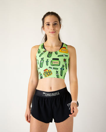 Runner is wearing ChicknLegs in the women's power crop top in the pickles design. The material is lightweight and the print has pickles all over it with yellow and green jars.