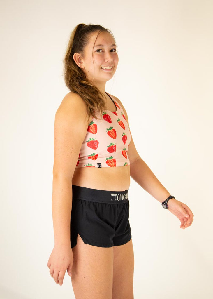 The model is wearing Chicknlegs women's pwr crop top in the strawberry szn design, facing right.