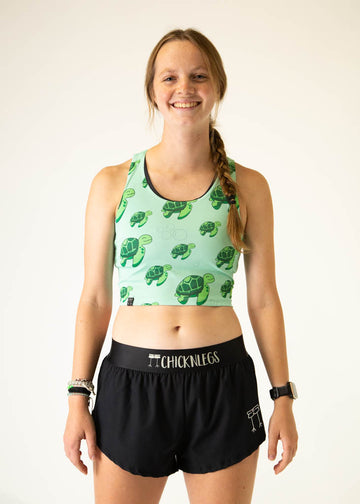 The model is a runner who is wearing Chicknlegs PWR crop top in the turtles design, facing front.