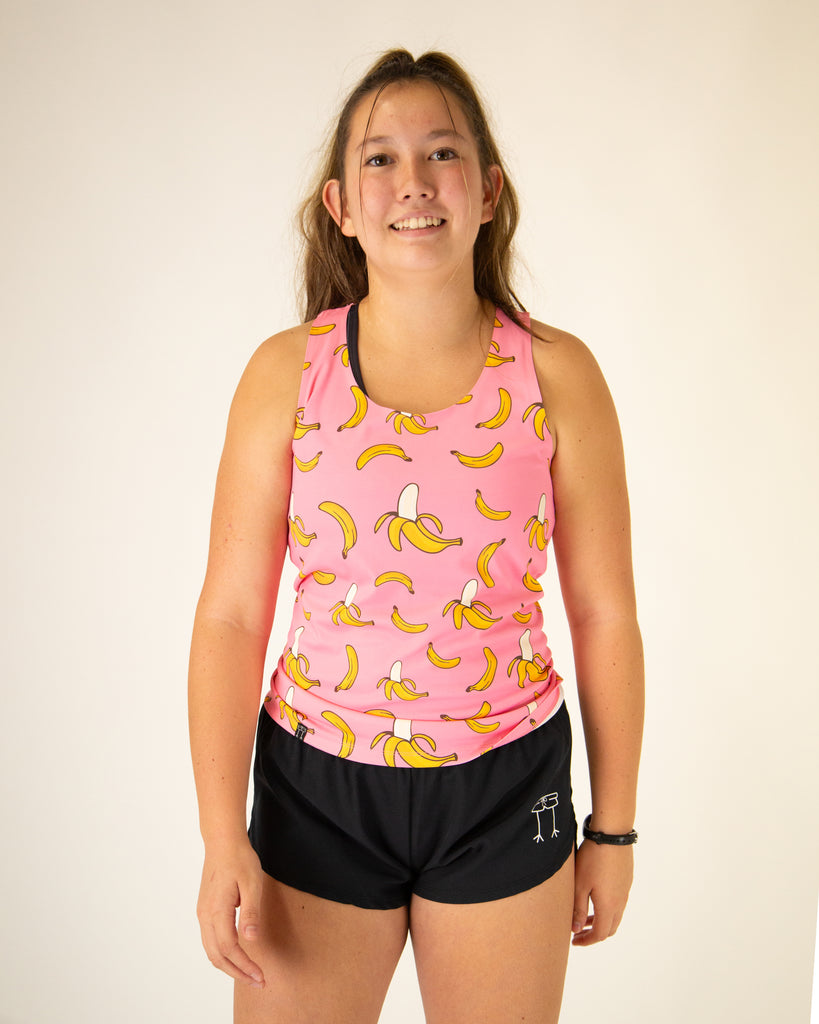 Runner is wearing ChicknLegs in the women's performance singlet in the pink bananas design, with a bright pink background with yellow bananas.