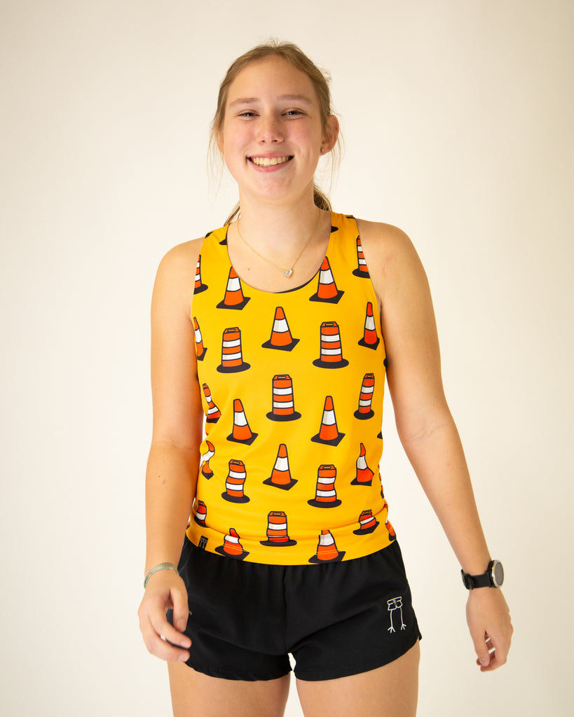 Runner is wearing ChicknLegs in the women's singlet in the traffic cones design, with a yellow orange background with orange traffic cones all over it.