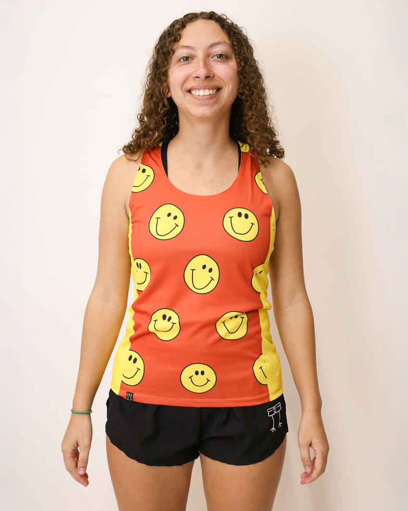 Runner is wearing ChicknLegs in the women's running performance side panel singlet in the smiley design. The print has bright yellow sides with an orange background and smiley faces over it.